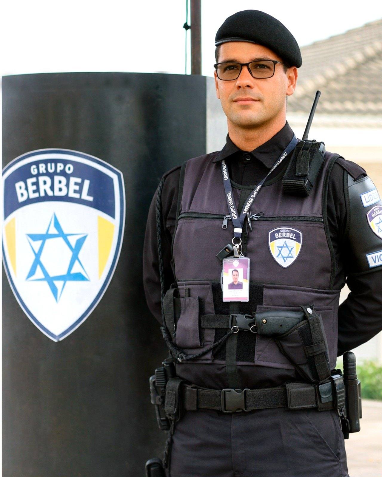Vigilante do Grupo Berbel ao lado do totem com o escudo da empresa